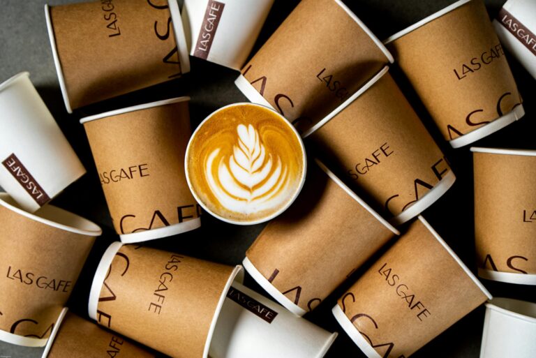 Top view of latte art coffee surrounded by Las Cafe paper cups. Perfect for beverage and cafe themes.